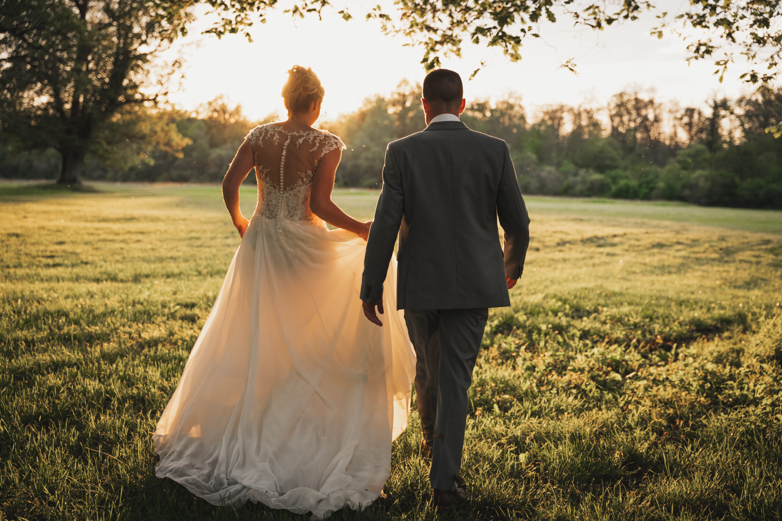 un couple des jeunes maries qui posent de dos au couché de soleil